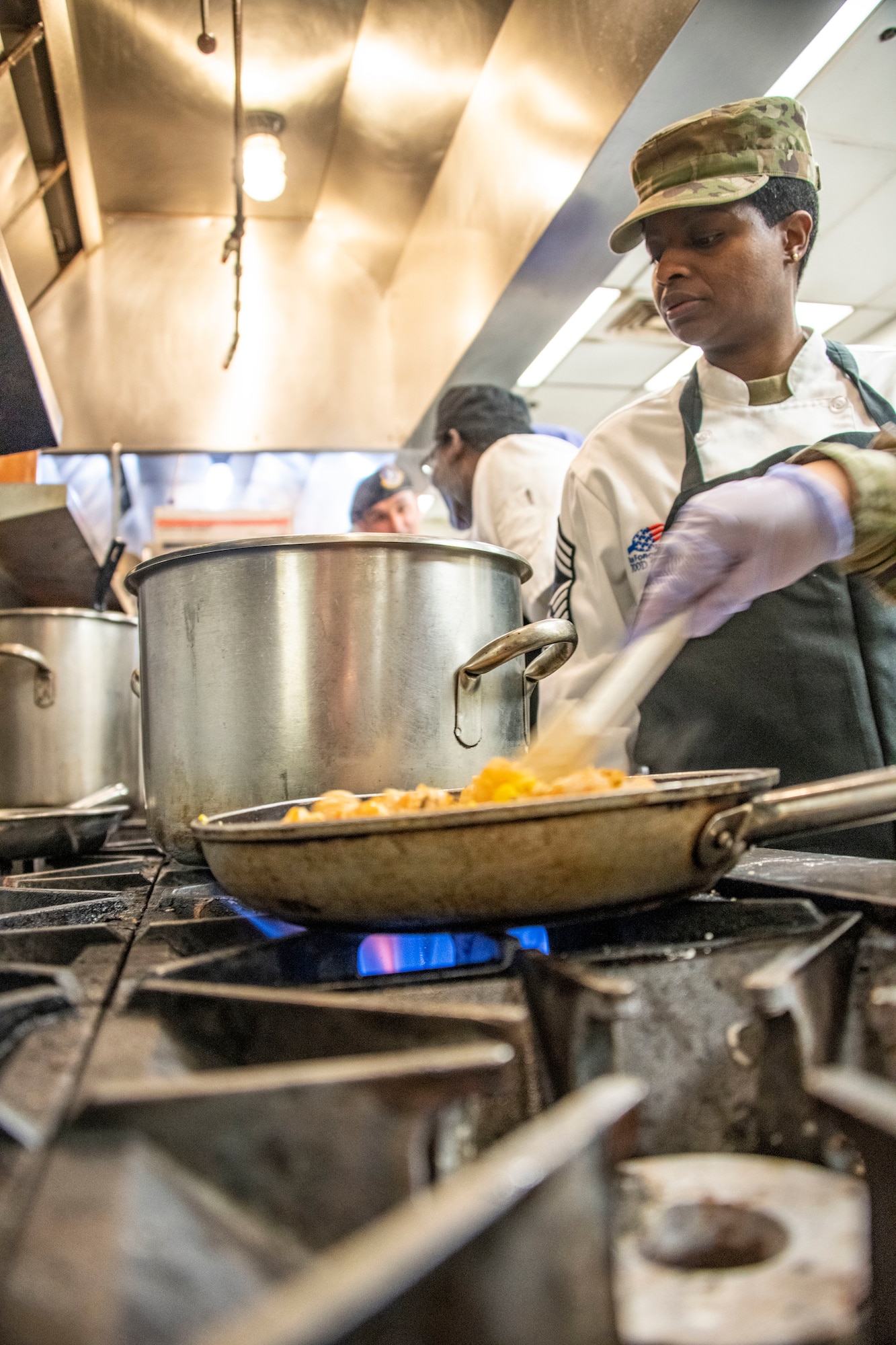 U.S. Air Force Chief Master Sgt. Andrea Conlan, 60th Force Support Squadron senior enlisted leader, monitors Team One’s cook pots during a chopped competition at Travis Air Force Base, California, March 23, 2022. The 60th Mission Support Group Monarch Dining Facility hosted a cooking competition showcasing skill, speed and ingenuity. Teams of four competed to transform mystery ingredients into the main course and dessert dishes to present to a panel of judges. (U.S. Air Force photo by Heide Couch)