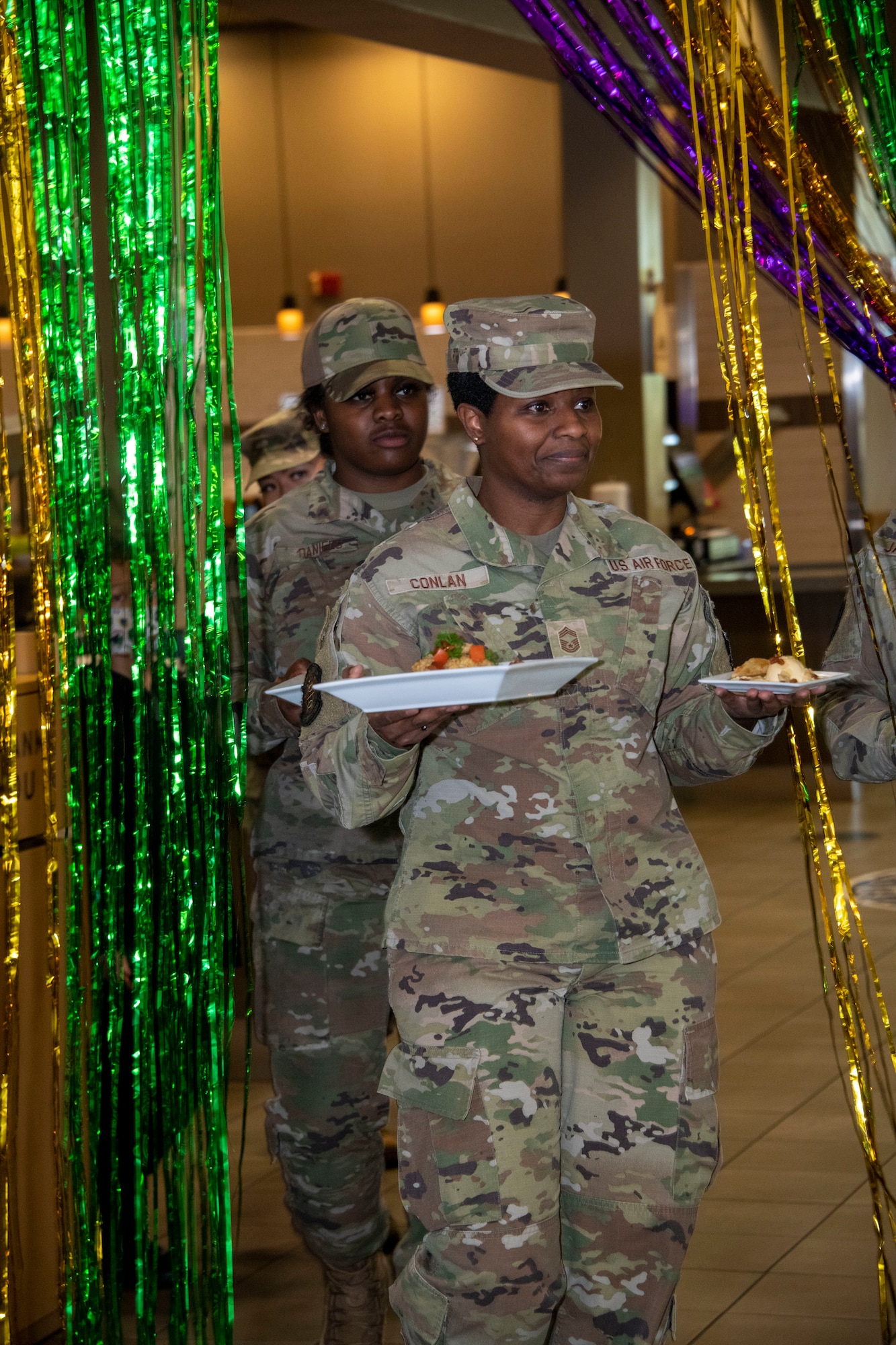 U.S. Air Force Chief Master Sgt. Andrea Conlan, 60th Force Support Squadron senior enlisted leader, leads Team One out be judged at Travis Air Force Base, California March 23, 2022. The 60th Mission Support Group Monarch Dining Facility hosted a cooking competition showcasing skill, speed and ingenuity. Teams of four competed to transform mystery ingredients into the main course and dessert dishes to present to a panel of judges. (U.S. Air Force photo by Heide Couch)