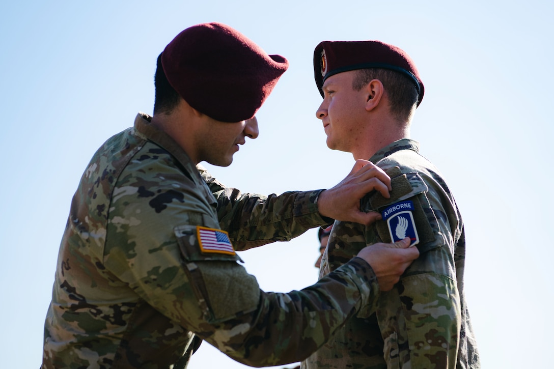 An Army paratrooper puts a unit patch on the arm of another officer during a unit patching ceremony.