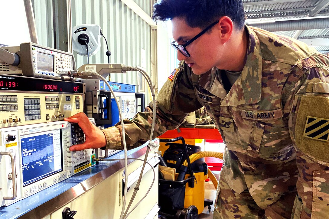 A soldier checks the settings on a piece of test equipment.