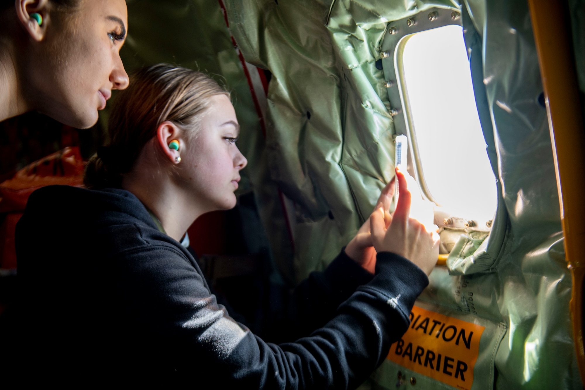 Development and Training Flight trainees peer out the window of a KC-135R Stratotanker during an incentive flight, March 5, 2022, Grissom Air Reserve Base, Indiana. The D&TF prepares the trainees for Basic Military Trainee and their future careers in the Air Force. (U.S. Air Force photo by Staff Sgt. Alexa Culbert)