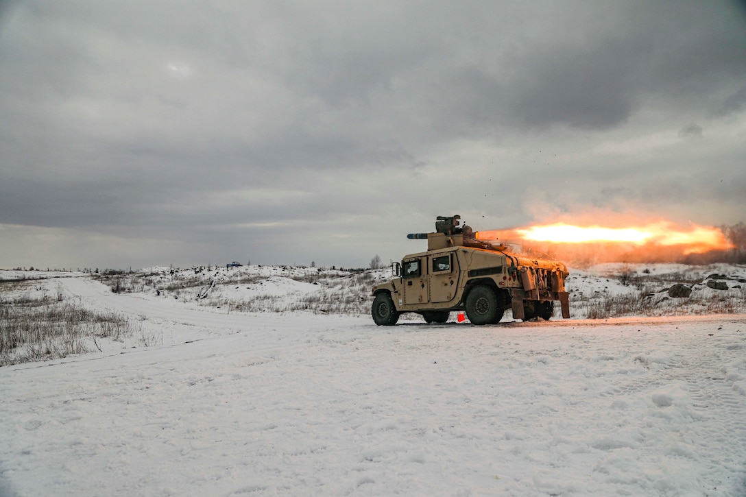 A soldier fires a missile from a vehicle parked in a snow-covered field.