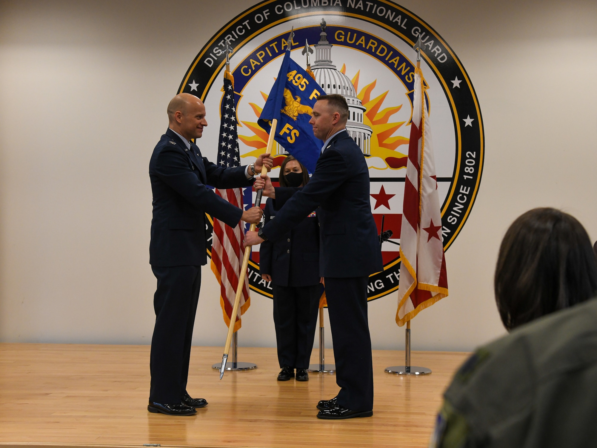 U.S. Air Force Col. Mark Massaro (left), commander of the 495th Fighter Group, passes the unit guidon at the activation ceremony of the 53rd Fighter Squadron at the D.C. Air National Guard 113th Wing auditorium, Joint Base Andrews, Maryland, Dec. 10th, 2021. The 53rd, a historic unit with roots in World War Two, was reactivated as a partner unit to the 113th as part of the U.S. Air Force Total Force Initiative, which pairs active duty personnel with National Guard counterparts for training and operations. As of the activation, 51 active duty airmen were assigned to the 53rd. Air Force Lt. Col. James Wentzel (right) assumed command of the unit in the ceremony. (U.S. Air National Guard photo by Tech. Sgt. Andrew Enriquez)