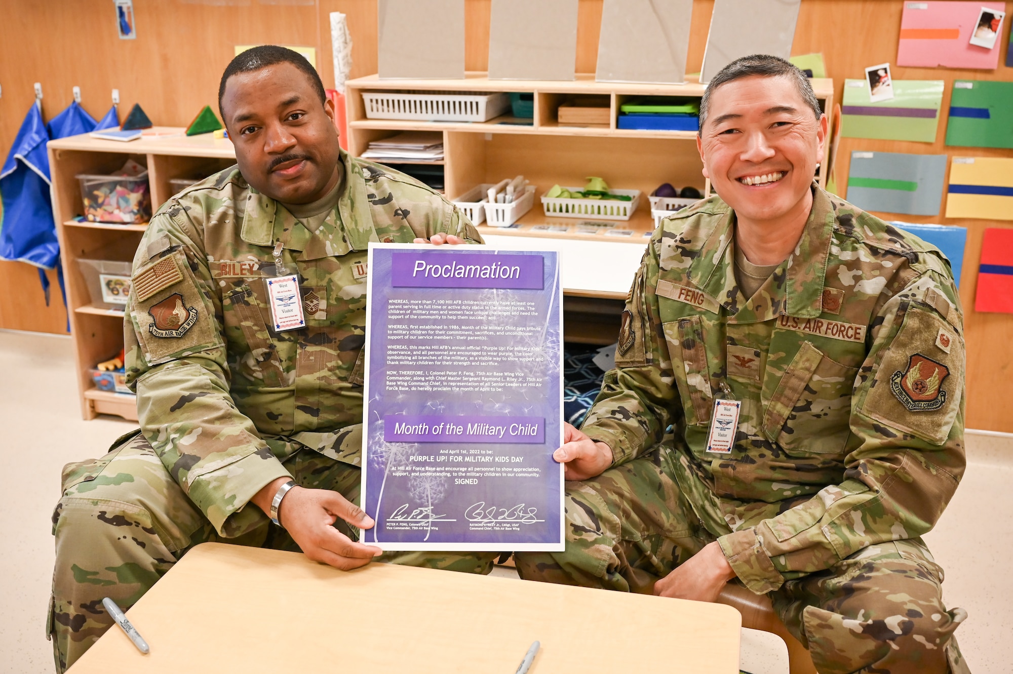 Chief Master Sgt. Raymond Riley, 75th Air Base Wing command chief, and Col. Peter Feng, 75th ABW vice commander, hold up the Month of the Military Child proclamation during a visit to the Child Development Center March 29, 2022, at Hill Air Force Base, Utah.