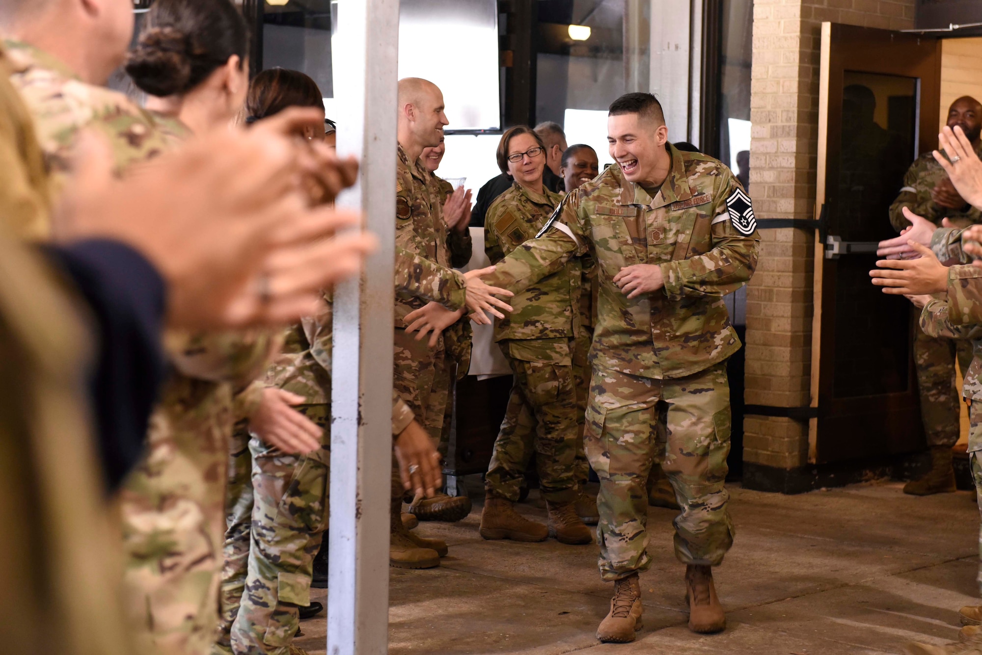 Air Force man walks down aisle of cheering airmen.