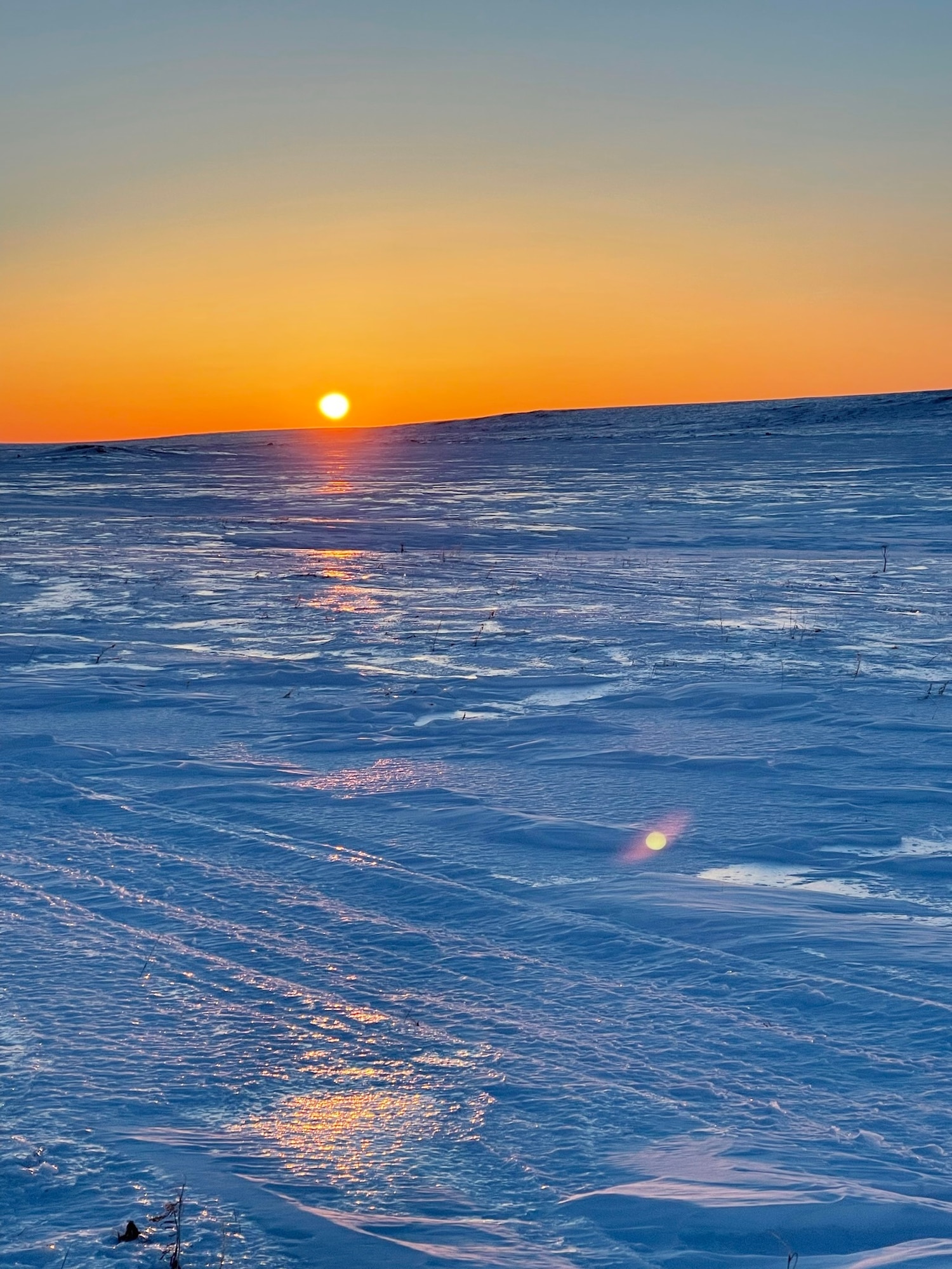 A photo of the sun rising above an icy landscape.