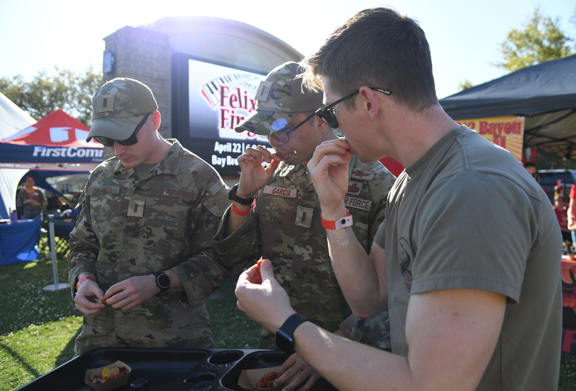 U.S. Air Force 2nd Lts. Hunter Cantrell, Edward Garcia and Andrew Bemis, 333rd Training Squadron students, sample boiled crawfish and side dishes during the 10th Annual Crawfish Cook-Off at the Bay Breeze Event Center on Keesler Air Force Base, Mississippi, March 25, 2022. More than 20 teams competed in the event and more than 1,500 pounds of crawfish were distributed. (U.S. Air Force photo by Kemberly Groue)