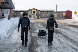 Maj. Joshua Brown and fellow competitor walk down a street in Nome, Alaska