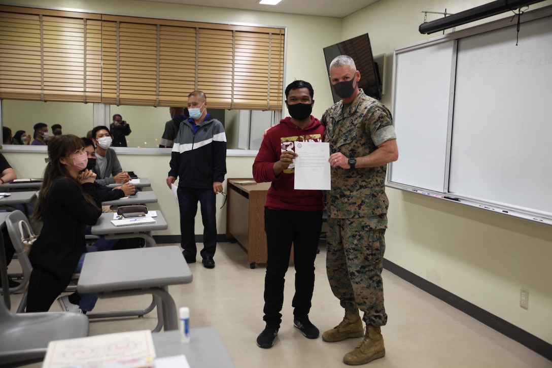 沖縄県名護市にあるアメリカ海兵隊基地キャンプ・シュワブで３月２９日夜、「社会人英語講座プログラム」の２０２１年度終業式が執り行われ、マシュー・トレーシー基地司令官から感謝状を受け取った６か月の部隊配置計画で沖縄を訪れている海兵隊少尉。