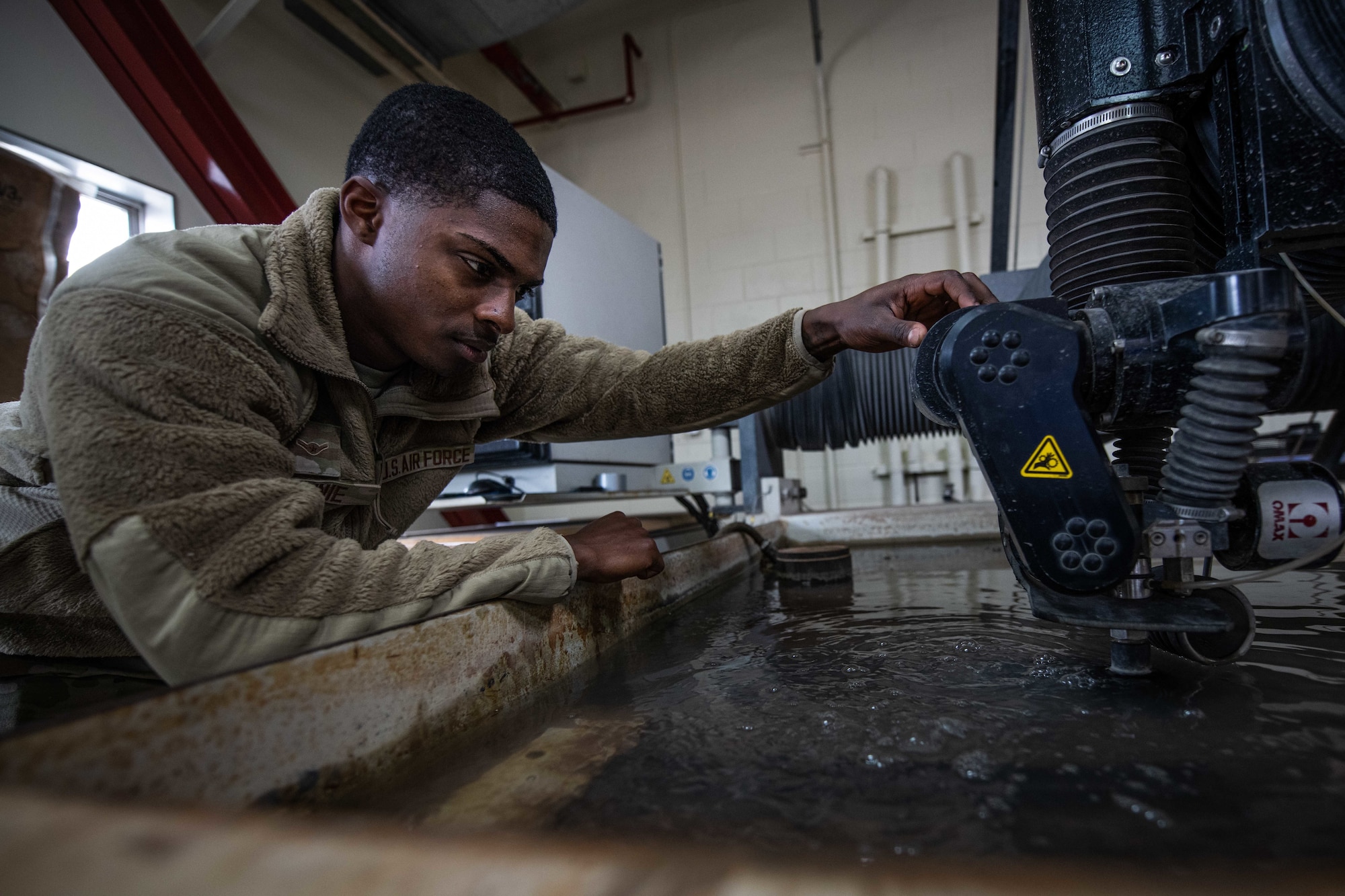 Airman uses water jet machine to cut metal