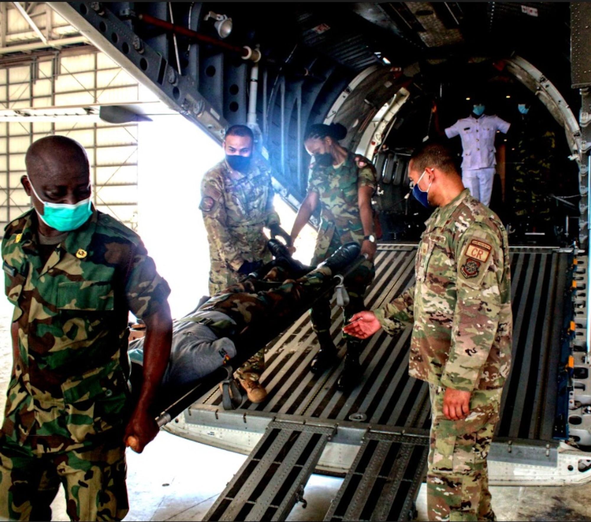 U.S. Air Force Master Sgt. Arthur Tewasiliig, right, 818th Mobility Support Advisory Squadron air advisor, and Staff Sgt. Sean McCurbin, left center, 621st Air Mobility Advisory Group air advisor, assist Ghanaian Armed Forces members with aeromedical evacuation training March 2, 2022, at Air Force Base Accra, Ghana. Air advisors deployed to Ghana in support of the U.S. Africa Command’s African Peacekeeping Rapid Response Partnership Training program to prepare Ghanaian forces for an upcoming U.N. deployment. (Courtesy photo)