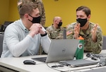 Capt. Sean Smith, right, deputy cyber chief for the Defensive Cyber Operations Element, and a Lebanon, Pa., native, discusses with a Penn State student during the PA National Guard Wi-Fighter Cyber Challenge at Penn State University on March 16, 2022. Smith, also a Penn State alum, assisted students to finish the competition.