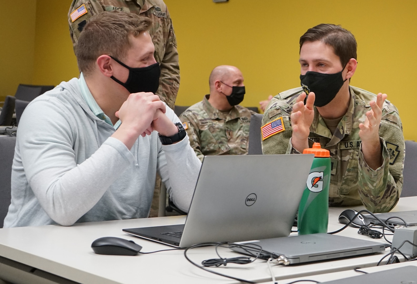 Capt. Sean Smith, right, deputy cyber chief for the Defensive Cyber Operations Element, and a Lebanon, Pa., native, discusses with a Penn State student during the PA National Guard Wi-Fighter Cyber Challenge at Penn State University on March 16, 2022. Smith, also a Penn State alum, assisted students to finish the competition.