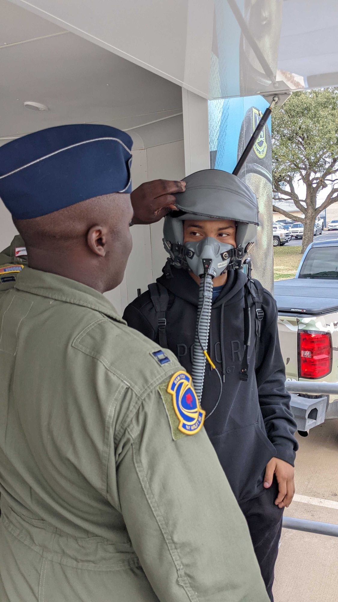 Capt. Wesley Cobb (left), a C-40 B/C pilot from the 1st Airlift Squadron at Joint Base Andrews, Maryland, helps a student try on a flight helmet at one of several schools he visited in Houston as a volunteer with Air Force Recruiting Service Detachment 1