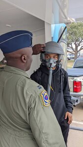 Capt. Wesley Cobb (left), a C-40 B/C pilot from the 1st Airlift Squadron at Joint Base Andrews, Maryland, helps a student try on a flight helmet at one of several schools he visited in Houston as a volunteer with Air Force Recruiting Service Detachment 1