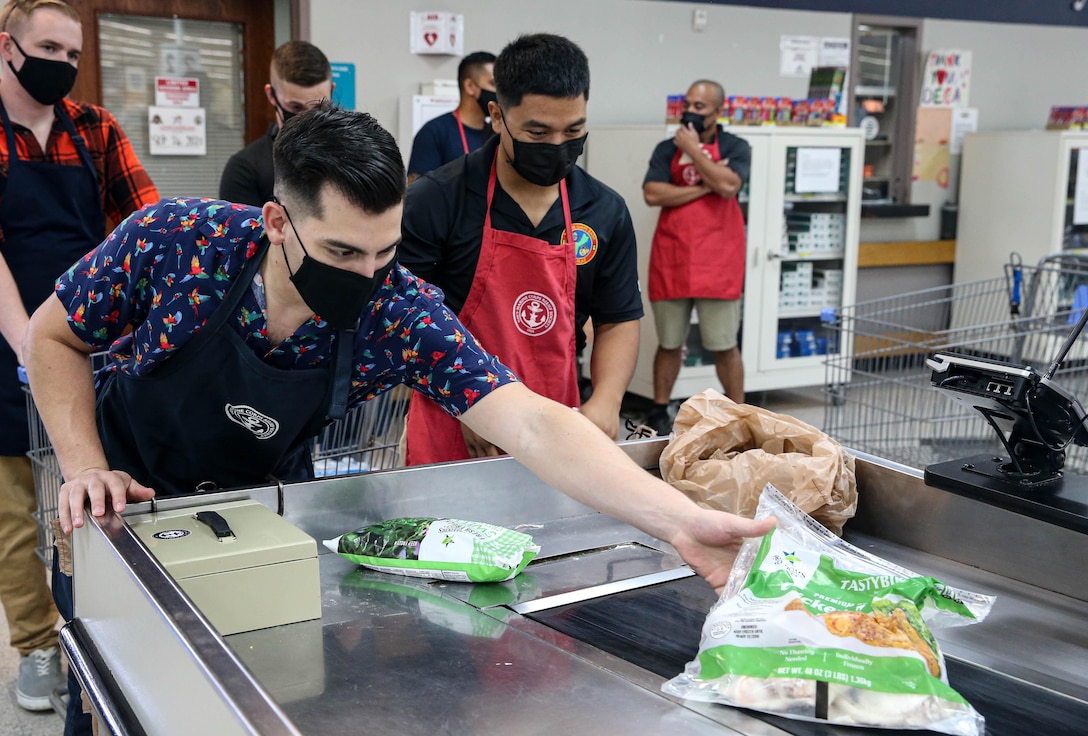 U.S. Marine Corps Capt. Joshua Oblea, the communications officer for Marine Corps Base Camp Blaz, left, volunteers with Cpl. Donald Pangelinan, training non-commissioned officer for Marine Corps Base Camp Blaz, right, during an event held by the Navy-Marine Corps Relief Society (NMCRS) at the base commissary aboard Naval Base Guam, March 25, 2022. The NMCRS is a non-profit organization that helps active duty Sailors and Marines deal with crises, schedule and pay for emergency travel, and provides care for their families in times of need. (U.S. Marine Corps photo by Gunnery Sgt. Rubin J. Tan)