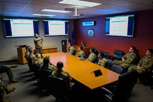 A photo of an airmen speaking at the head of a conference table