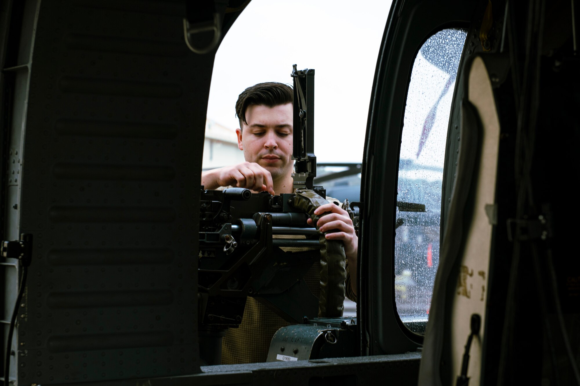 An airman from checks the chamber on a GAU-18 heavy machine gun