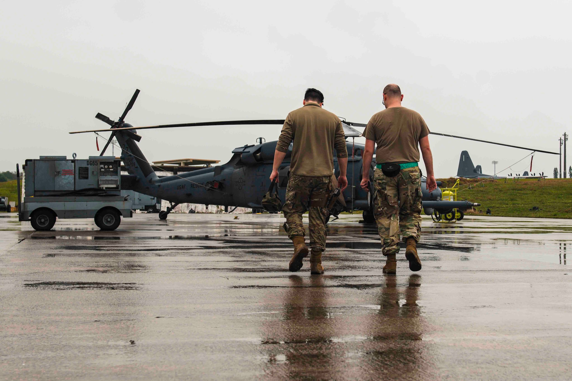 Airmen walk towards an HH-60G Pave Hawk helicopter