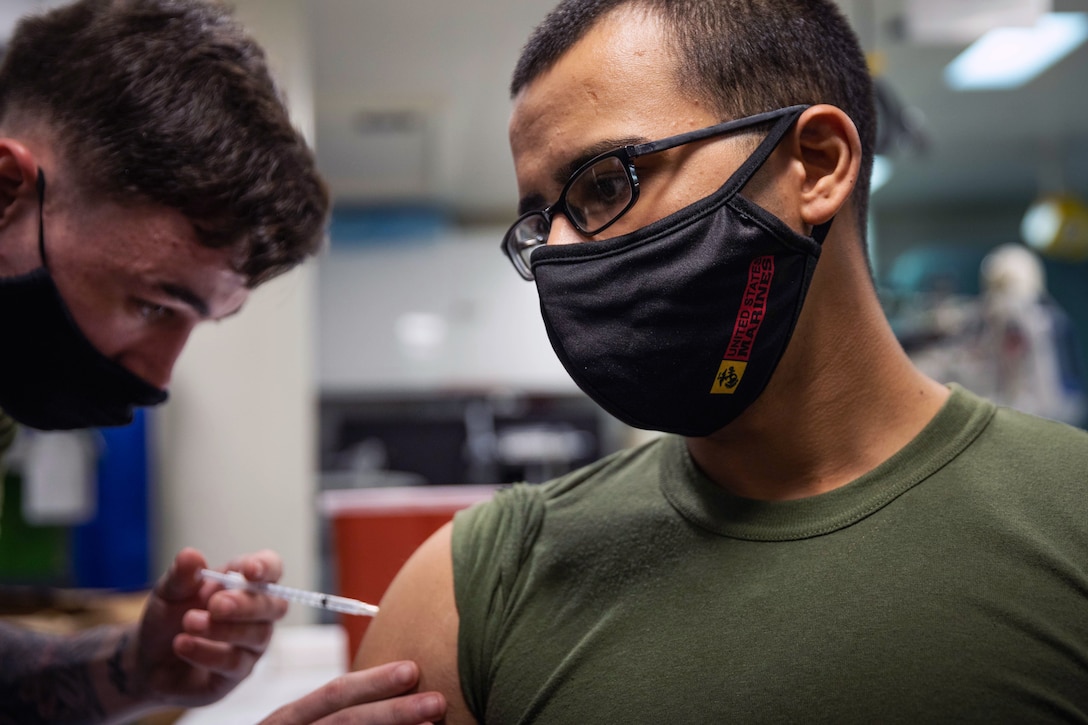 A Marine wearing a face mask receives a COVID-19 booster shot.