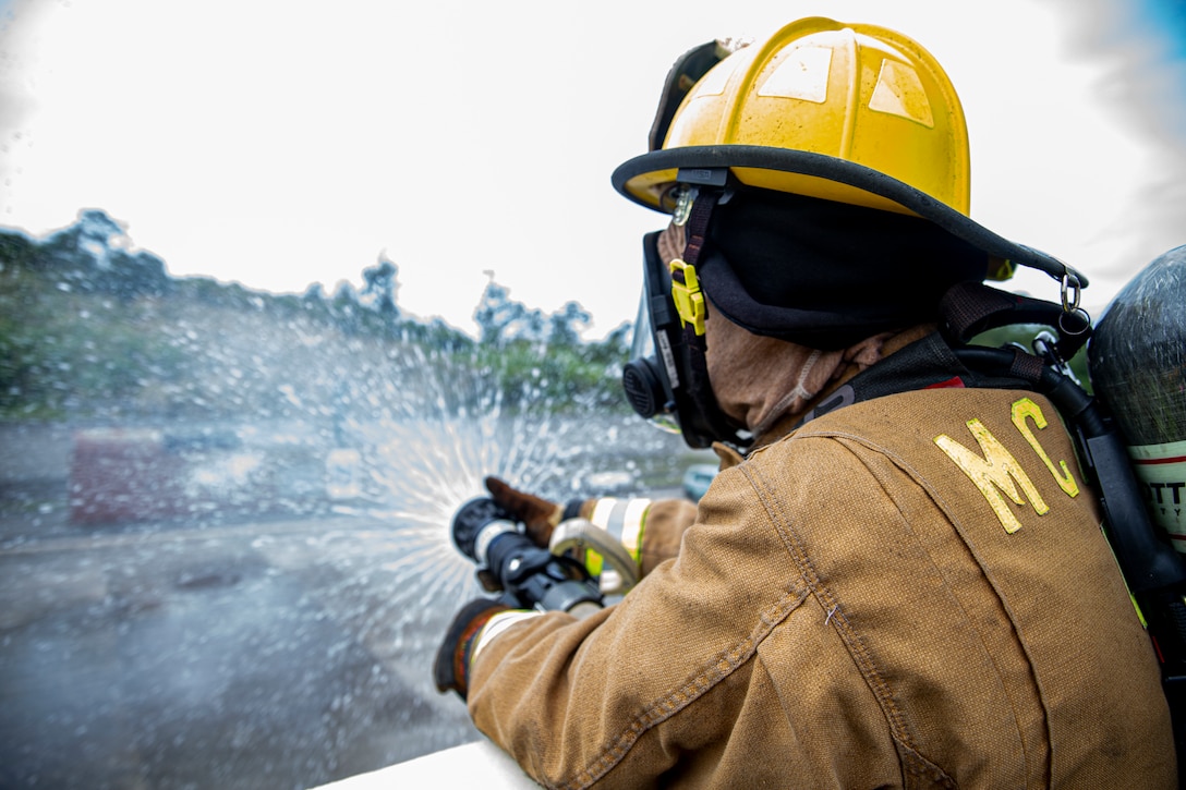 A firefighter with Marine Corps Installations Pacific Fire and Emergency Services expels excess water from a hose after bilateral live-fire training on Camp Hansen, Okinawa, Japan, March 25, 2022. MCIPAC F&ES and the Naha City Fire Department assembled and conducted live-fire training to compare the different firefighting techniques and methods each department uses to accomplish the same mission.