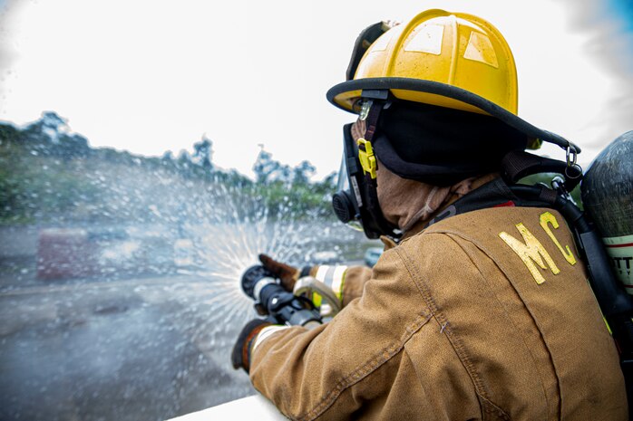 A firefighter with Marine Corps Installations Pacific Fire and Emergency Services expels excess water from a hose after bilateral live-fire training on Camp Hansen, Okinawa, Japan, March 25, 2022. MCIPAC F&ES and the Naha City Fire Department assembled and conducted live-fire training to compare the different firefighting techniques and methods each department uses to accomplish the same mission.