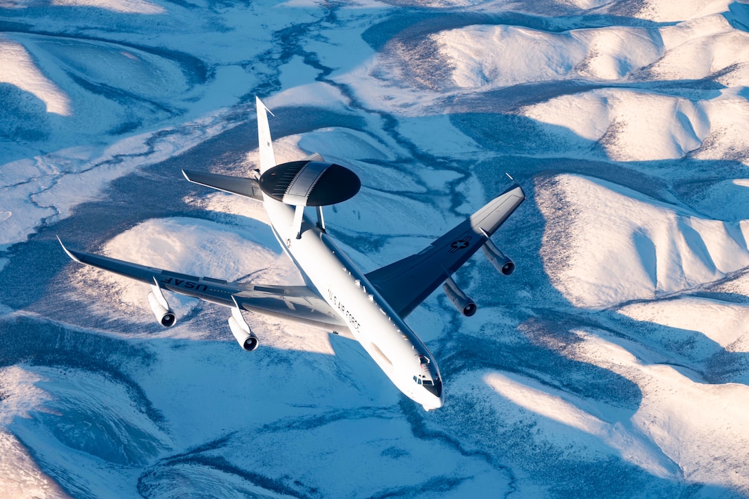 An aircraft flies over snow-covered mountains during training.