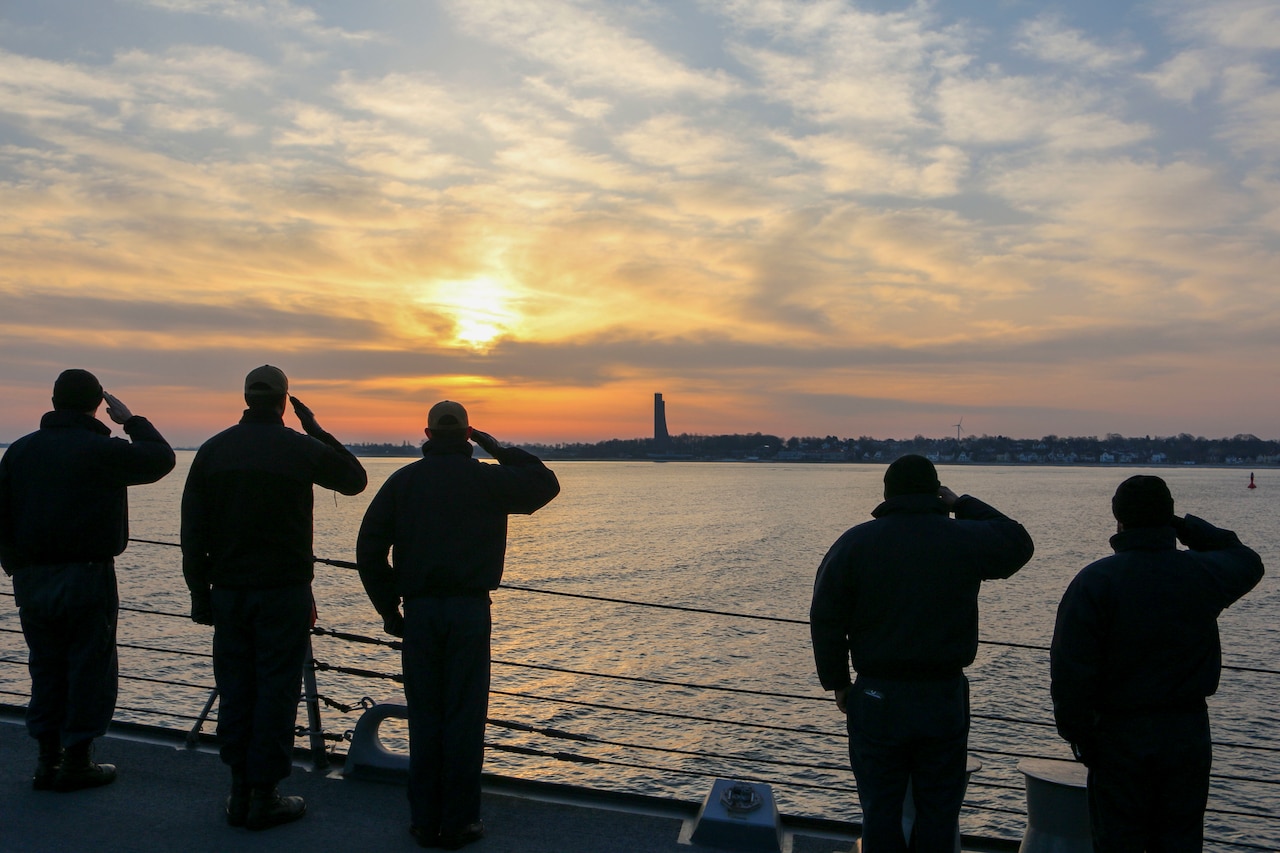 Sailors salute from a ship deck.