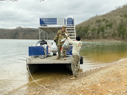 Lt.Col Nathan Branen loads trash onto pontoon for shoreline cleanup. (USACE Photo by HEATHER KING)