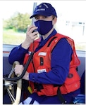 Auxiliarist Tiffany Townsend at the helm of the Auxiliary vessel Silver Charm, conducting a pre-mission equipment check. Photo by Coast Guard Auxiliarist Roger Bazeley.