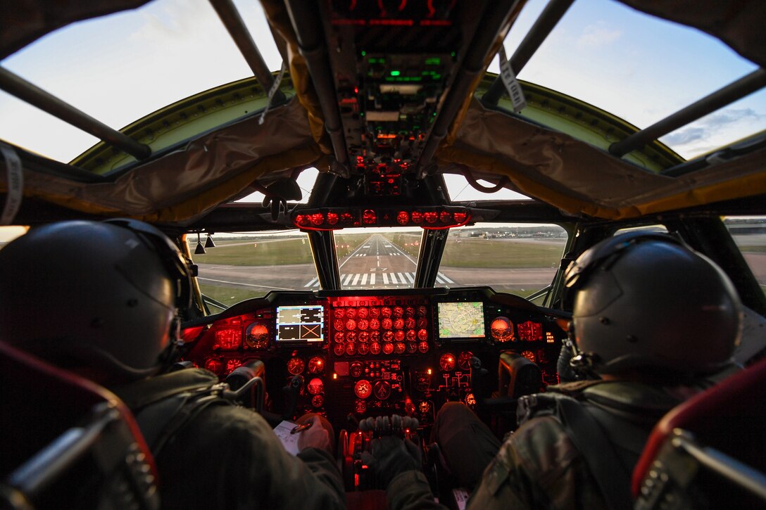 Pilots in a plane's cockpit look out at a runway.