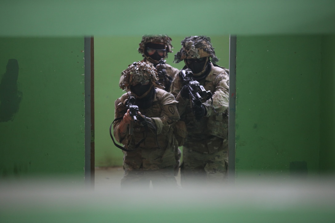 Soldiers point their weapons as they enter a room.