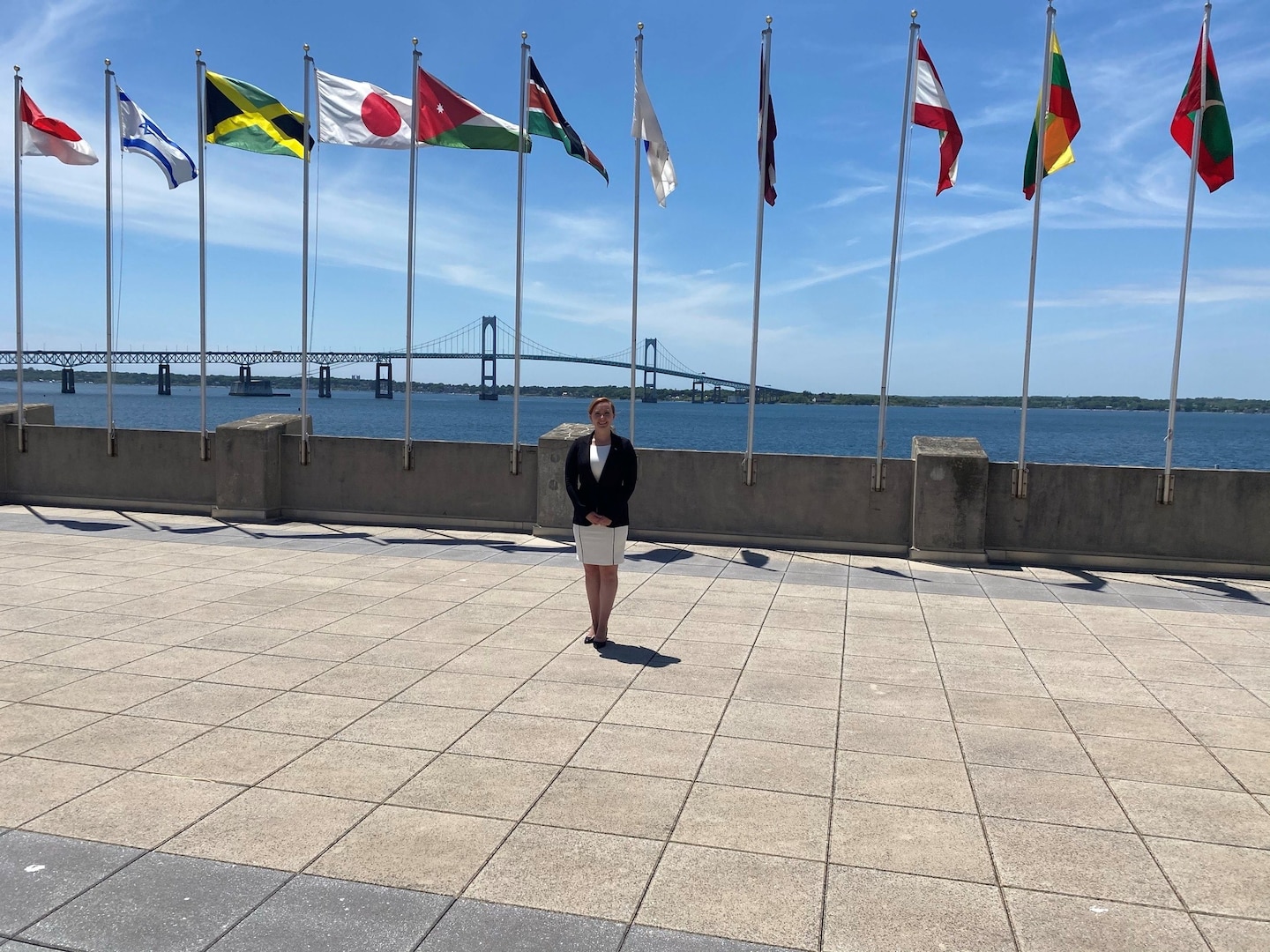 IMAGE: Emily Hester, lead systems engineer at Naval Surface Warfare Center Dahlgren Division, poses for a photo by the Naval War College flags. Hester and four other Naval Sea Systems Command civilians learned alongside active duty military personnel from all the branches during the ten month Bundy Scholars program.
