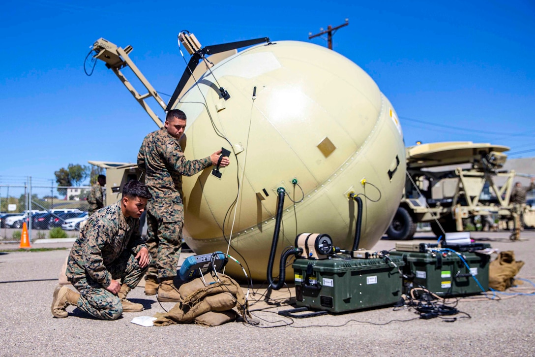 Two Marines work on military communication equipment.