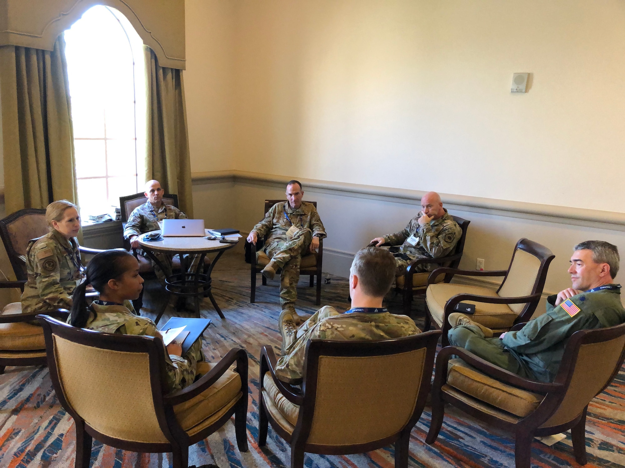Seven Air Force members sit in a circle talking together.