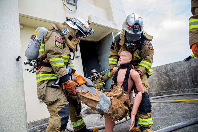 Firefighters with the Naha City Fire Department respond to a fire during a bilateral live-fire training exercise on Camp Hansen, Okinawa, Japan, March 25, 2022. Marine Corps Installations Pacific Fire and Emergency Services and the Naha City Fire Department assembled and conducted live-fire training to compare the different firefighting techniques and methods each department uses to accomplish the same mission.