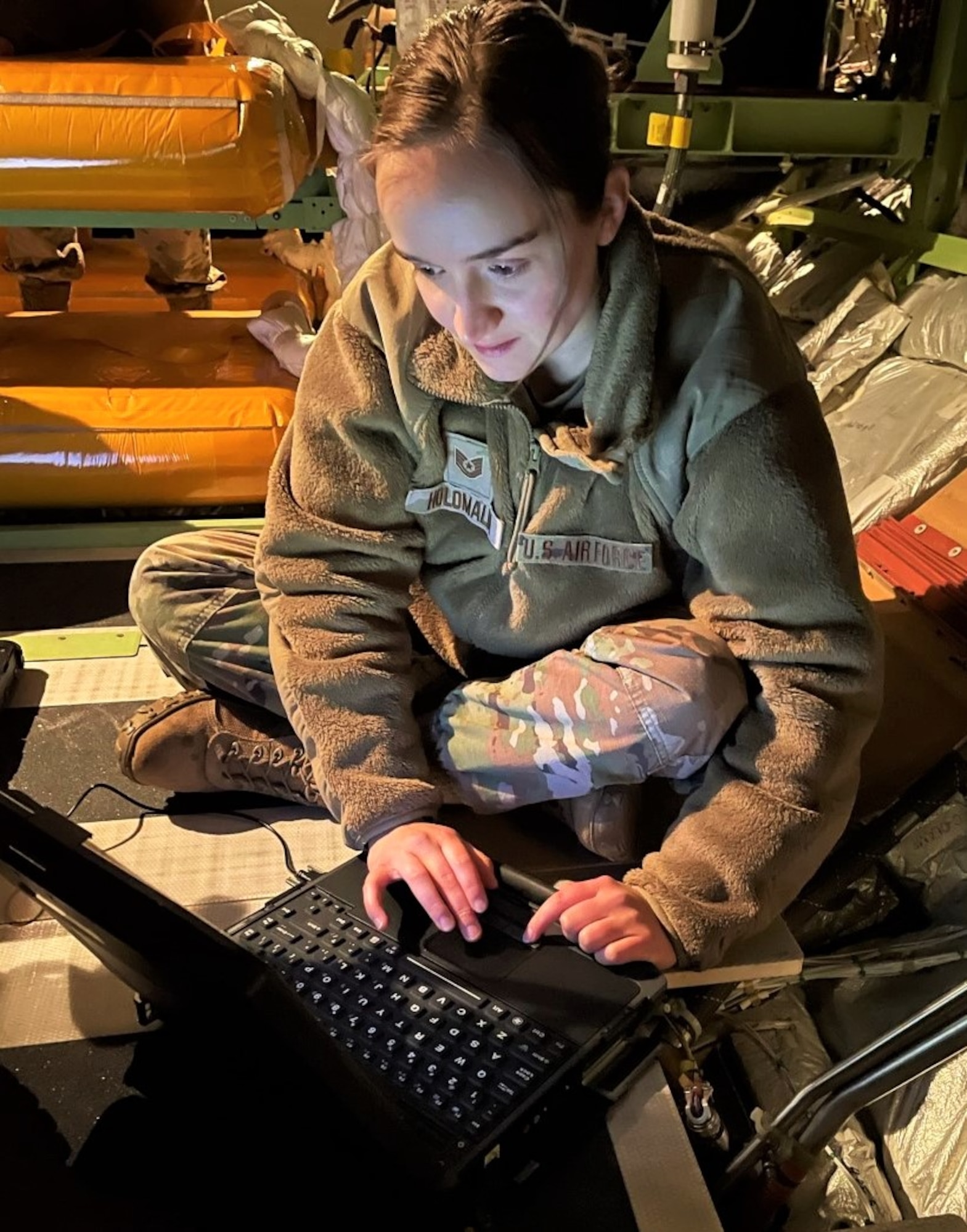 Tech. Sgt. Julie Holomalia programs on a laptop while sitting in a KC-46 Pegasus.