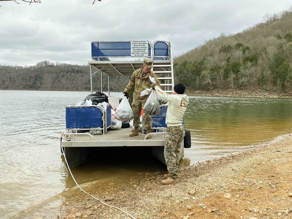 Lt.Col Nathan Branen loads trash onto pontoon for shoreline cleanup. (USACE Photo by HEATHER KING)