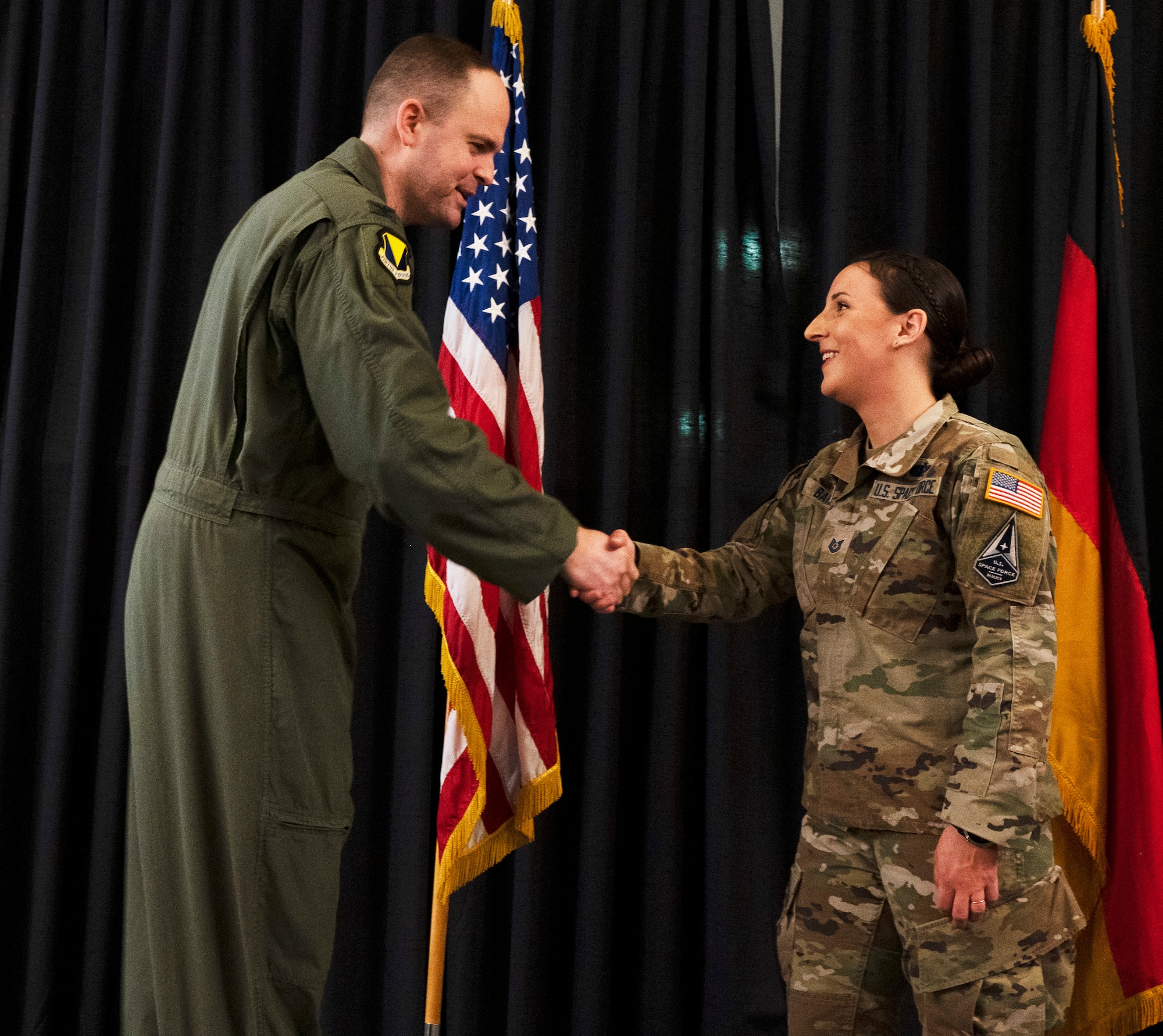 U.S. Space Force Tech. Sgt. Hollie Baire, 86th Communications Squadron non-commissioned officer in charge of the Technical Control Facility receives a coin from U.S. Air Force Col. Denny Davies, 86th Airlift Wing Vice Commander at an all call at Ramstein Air Base, Germany, March 24 2022. Baire was awarded the title of Airlifter of the Week due to her part in facilitating the installation of $750,000 of new Defense Information Systems. (U.S. Air Force photo by Senior Airman Thomas Karol)