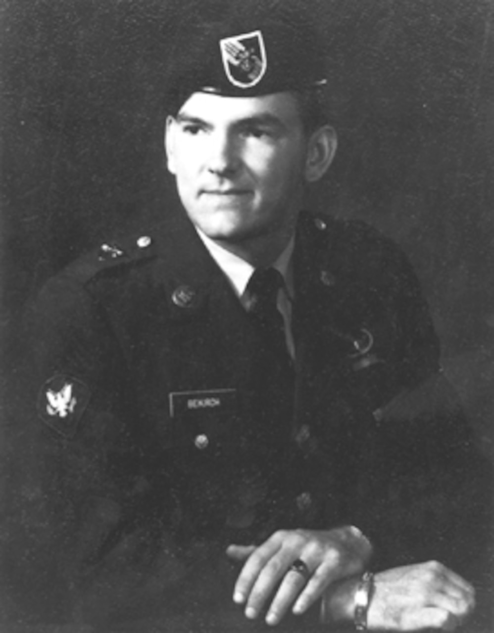 A man in dress uniform and beret poses for a photo.
