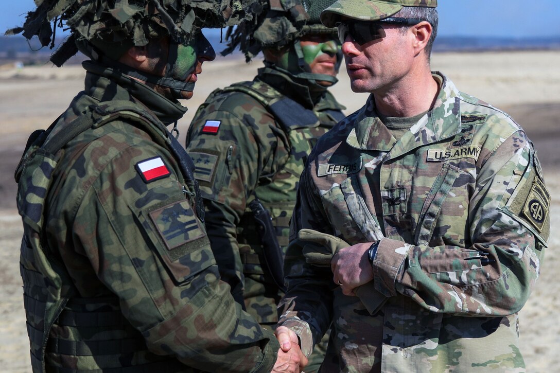 A soldier shakes hands with another service member.