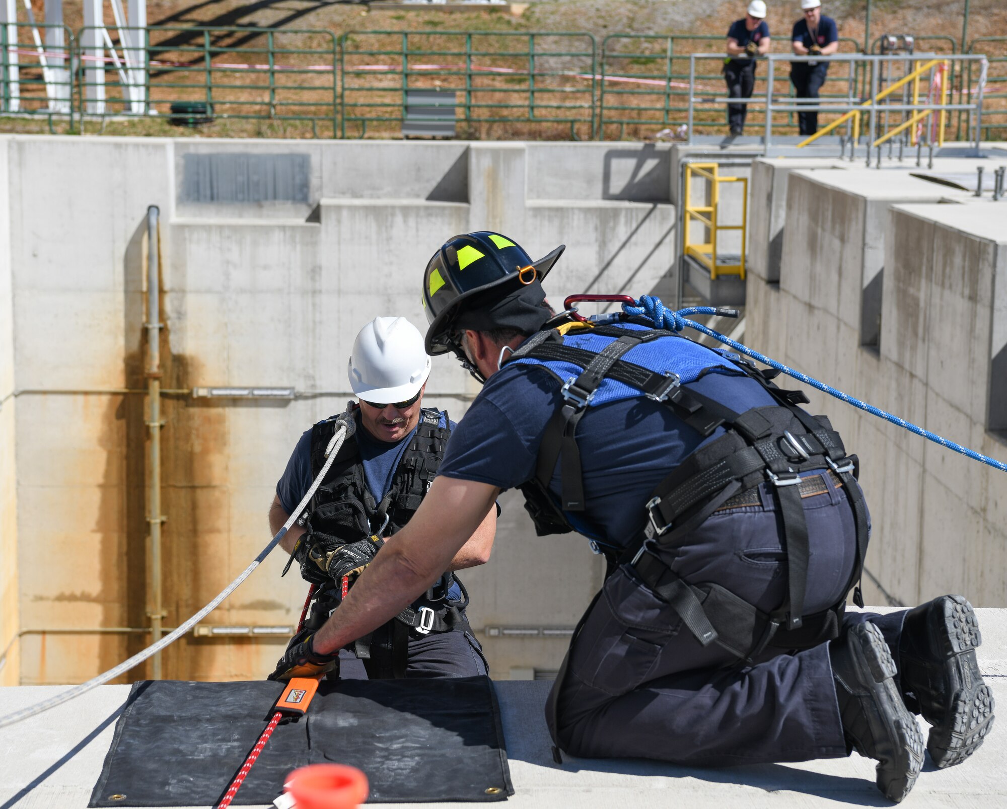 Firefighter positions rope guard as other firefighter rappels