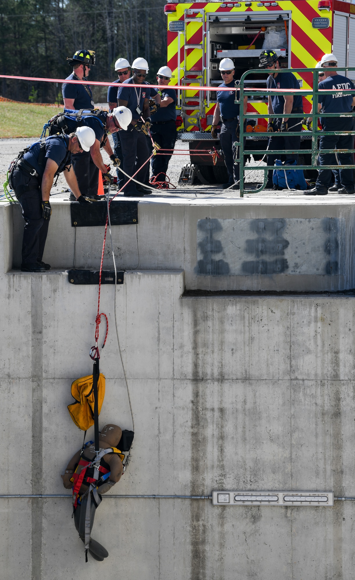 Training dummy being lifted via rope by firefighters