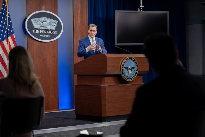 A man behind a lectern addresses people who are seated.