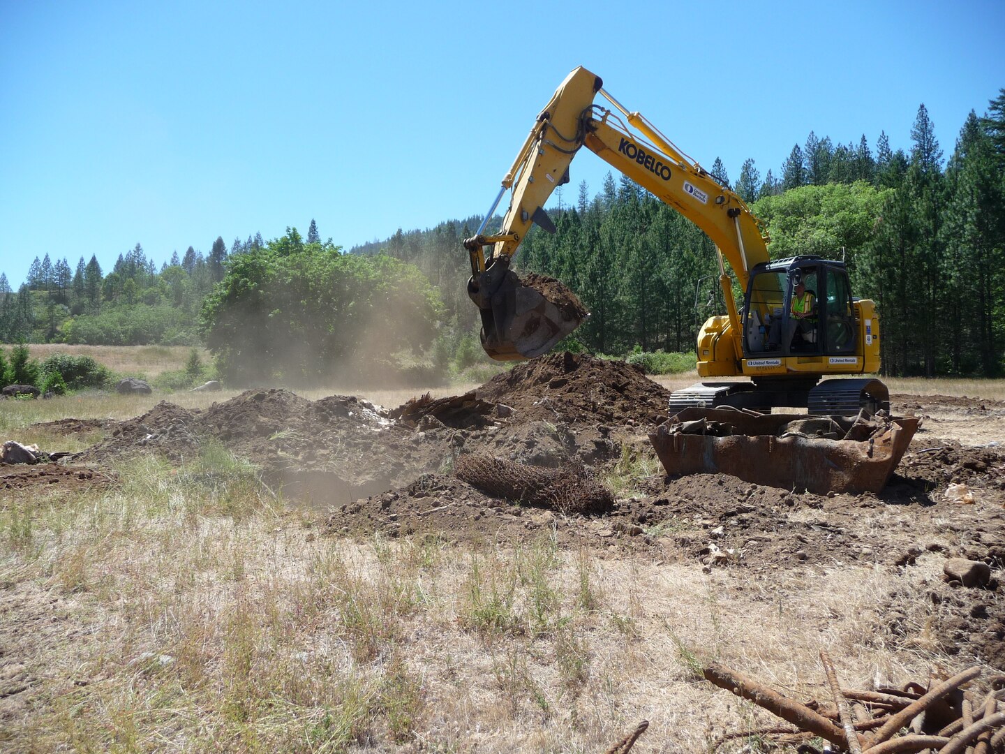 U.S. Army Corps of Engineers technicians confirm the presence of buried waste at Elk Creek Dam, 26 miles north of Medford, after digging test pits, Jun. 18, 2019. The Corps has made several investigations and waste removal efforts at the defunct dam site in the past; however, a 2019 complaint by a former contactor employee to ODEQ shed light on improper disposal by the Obayashi Corporation, the contractor the Corps used during construction.

“While the Corps and the Army Criminal Investigation Division work to hold the responsible party accountable for waste disposed on site, we’re continuing efforts to protect human health and the environment under the Superfund law (Comprehensive Environmental Response, Compensation, and Liability Act (CERCLA))”, said Tom Conning, Portland District spokesmen. “We take environmental protection seriously and will either cleanup the site itself or compel the responsible party to do so.”