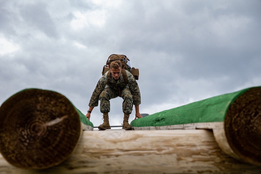 A Marine crouches on top of an obstacle.