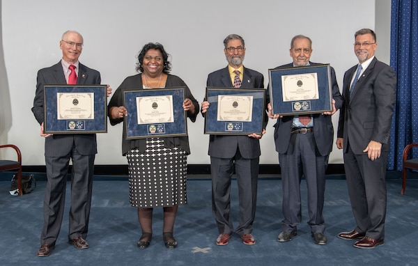 four people hold plaques