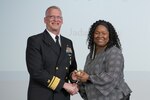 Navy Rear Adm. Grafton Chase, director of the DLA Joint Reserve Force and DLA CFC vice chair, passes the CFC campaign book to Sharyn Saunders, DLA Human Resources director and chair of the 2022 CFC campaign.  (Photo by Christopher Lynch, DLA Graphics-Multimedia Division)