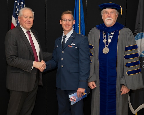 Secretary of the Air Force Frank Kendall presents a coin to 
a distinguished graduate prior to the Air Force Institute of Technology graduation ceremony in the National Museum of the U.S. Air Force at Wright-Patterson Air Force Base on March 24. Dr. Walter Jones, AFIT director and chancellor, joined Kendall in recognizing the distinguished graduates. (Air Force photo by R.J. Oriez)