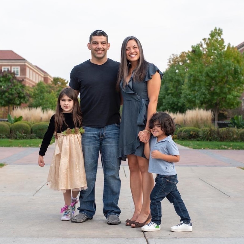 Two adults and two kids stand for a photo outside.